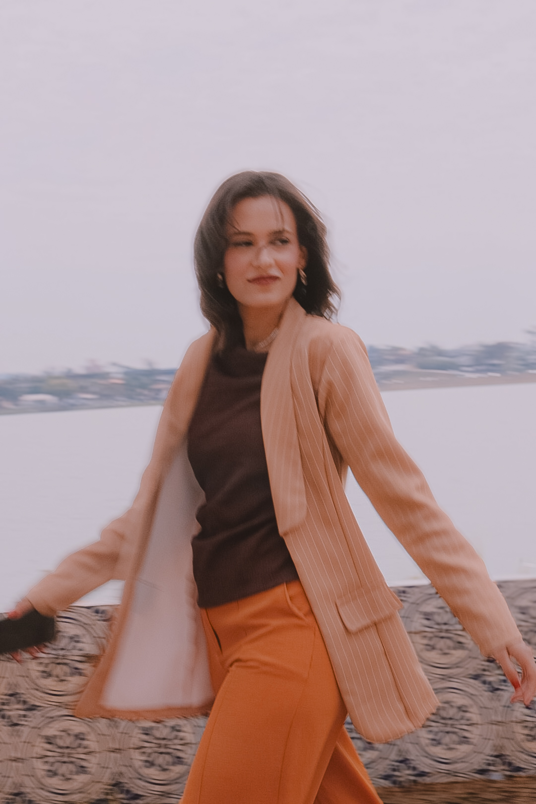 Débora Maia caminhando ao ar livre, em frente à água